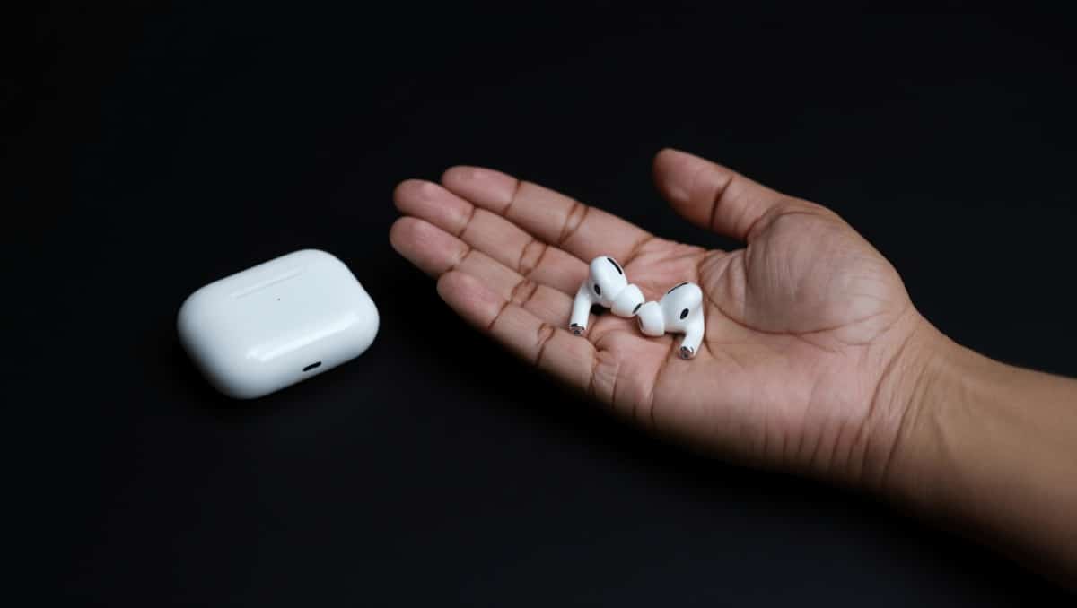 AirPods Pro mit Case im Vordergrund, geblurrter Kopf im Hintergund