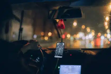 Fahrer mit Smartphone im Auto-Dashboard während der Fahrt