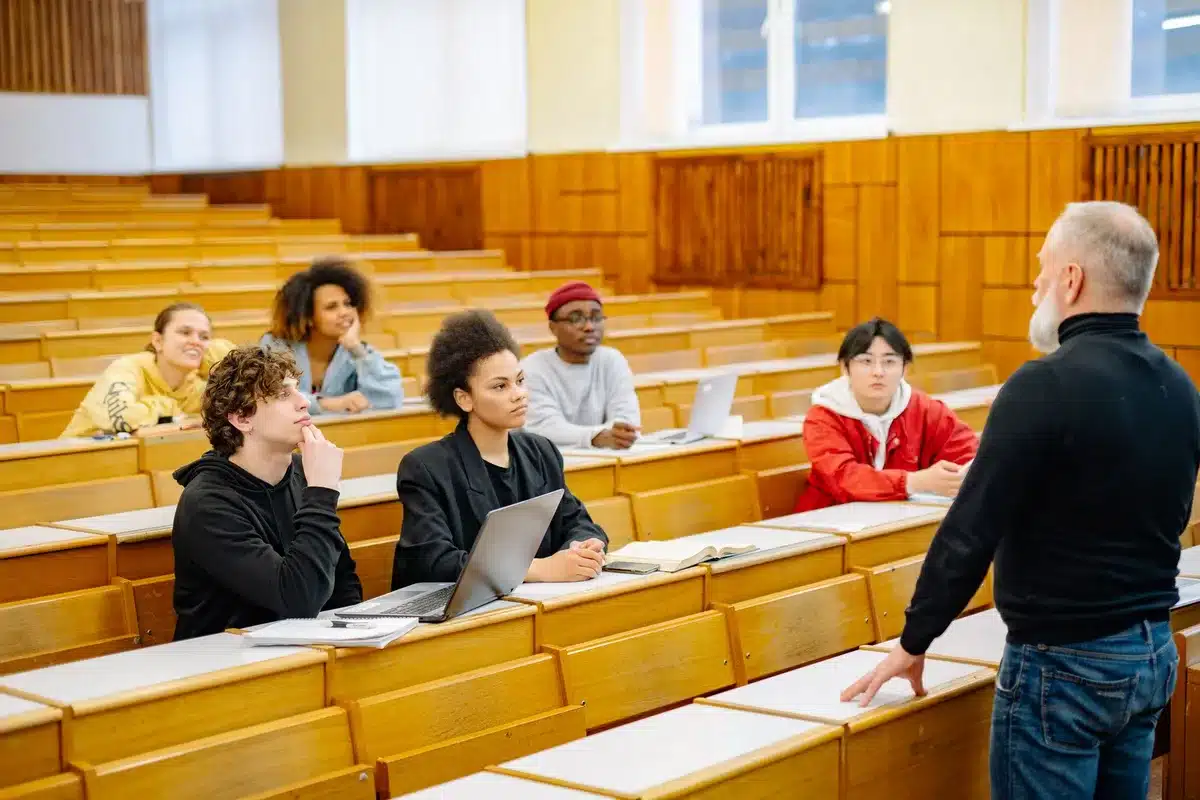 Schüler in einem Klassenzimmer arbeiten an Laptops und Notizbüchern.