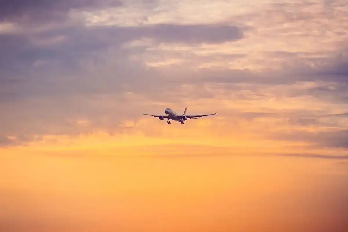 Smartphone zeigt Flugbuchungsseite mit niedrigen Preisen, im Hintergrund verschwommene Abflugtafel