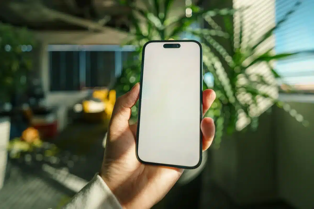 Hände halten ein modernes Smartphone mit leuchtendem Display und Kamera-Details