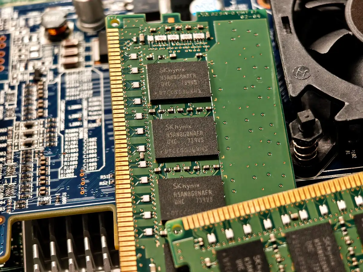 Defekte RAM-Module und Rechnungsunterlagen auf einem Schreibtisch neben einem Laptop