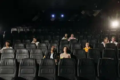 Kinobesucher sitzen im dunklen Saal und schauen auf eine riesige IMAX-Leinwand mit epischen Bildaufnahmen