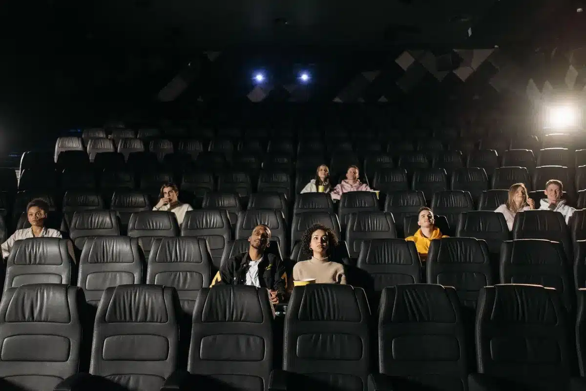 Kinobesucher sitzen im dunklen Saal und schauen auf eine riesige IMAX-Leinwand mit epischen Bildaufnahmen