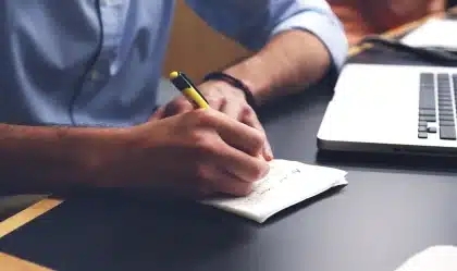 Hände über Rechnungen auf Schreibtisch mit Laptop und Paketkartons