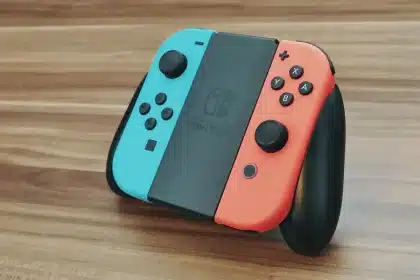 Anonyme Hände halten einen Controller vor leuchtender Spielkonsole mit Einkaufstüten im Hintergrund