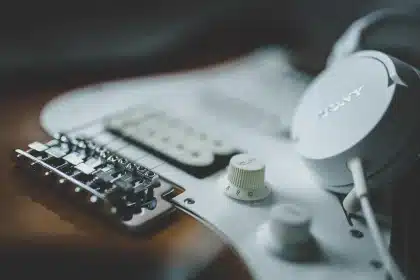 Silhouetten von Gitarrenkoffern und einem Resonator-Instrument auf dunkler Bühne, diffuse Lichter