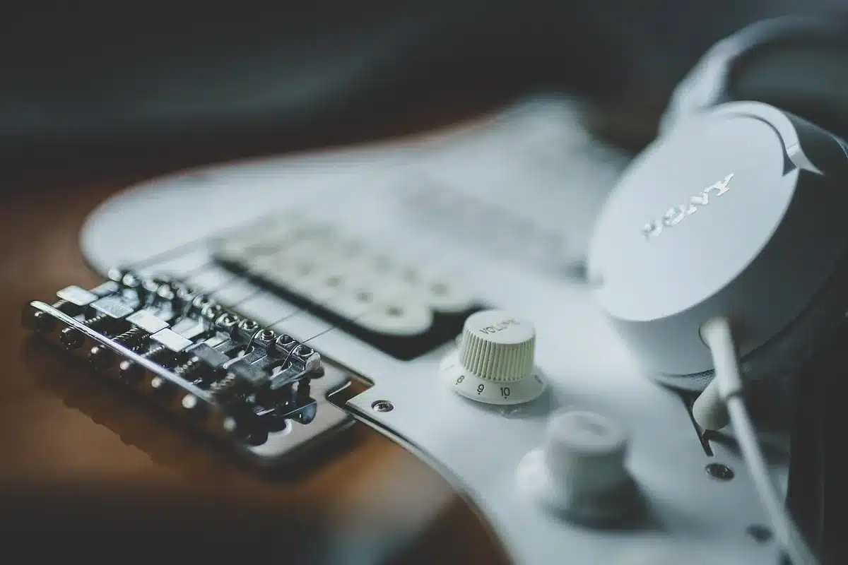 Silhouetten von Gitarrenkoffern und einem Resonator-Instrument auf dunkler Bühne, diffuse Lichter