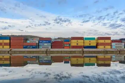 Anonymer Hof mit flexiblen Schläuchen und modularen Containern vor einem entfernten Traktor