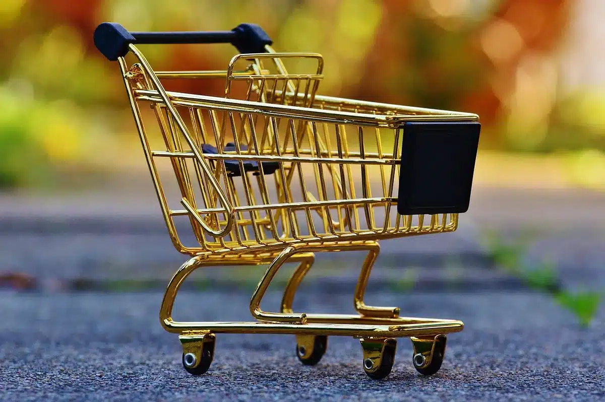 Kinderhände halten bunte Sammelsticker in einem Supermarkt mit Einkaufswagen