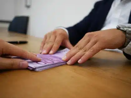 Person überprüft verwirrt Kontoauszüge und Transaktionen am Schreibtisch