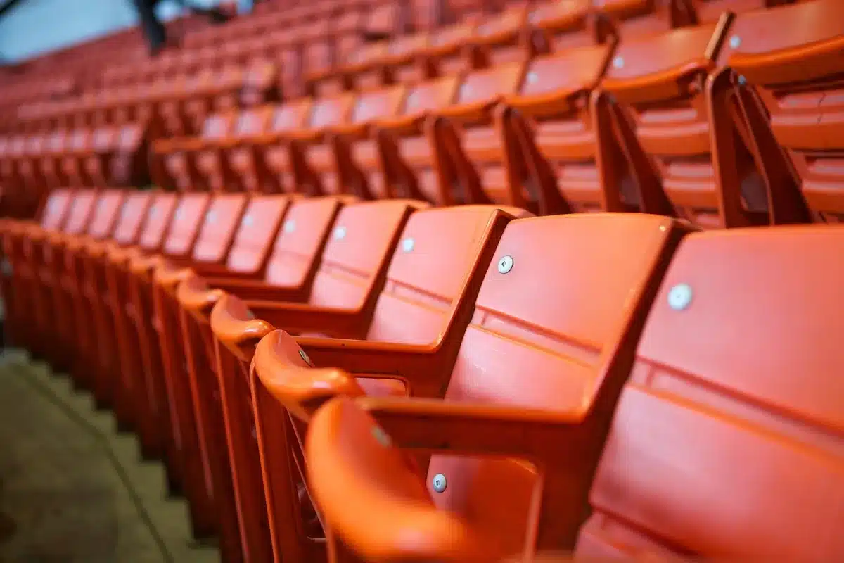 Leerer Stadionvorplatz mit Fanschal und Ticket in den Händen bei Dämmerung