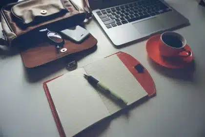 Anonymer Schreibtisch mit Notizbuch und Moodboard im Hintergrund, Studioatmosphäre