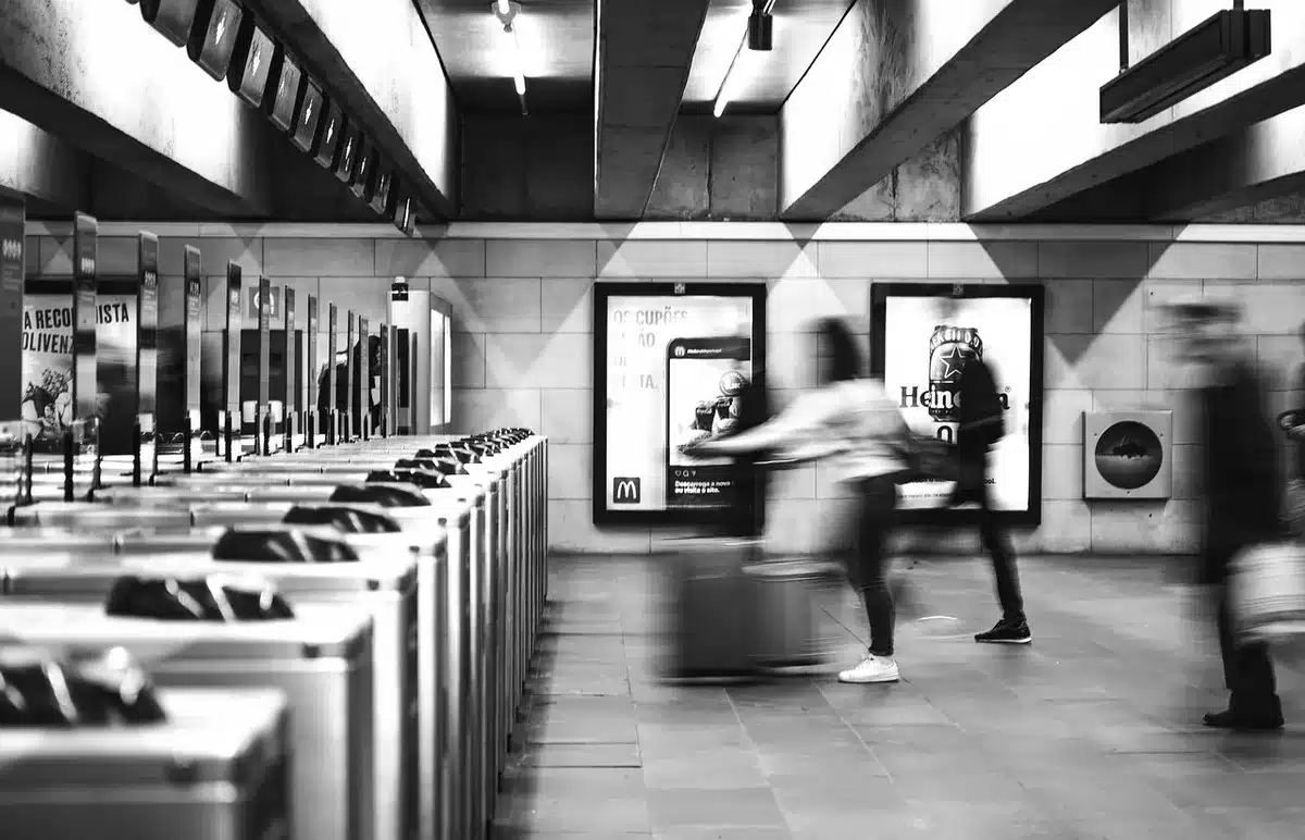 Anonyme Pendler mit Smartphone und Fahrkarte auf Bahnhofsbahnsteig