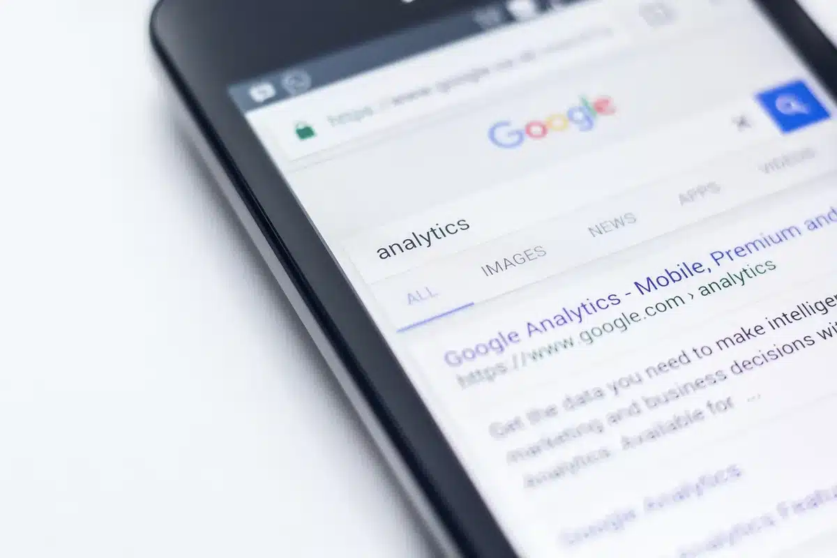 Person nutzt Smartphone zum Onlinekauf, mehrere Pakete im Hintergrund